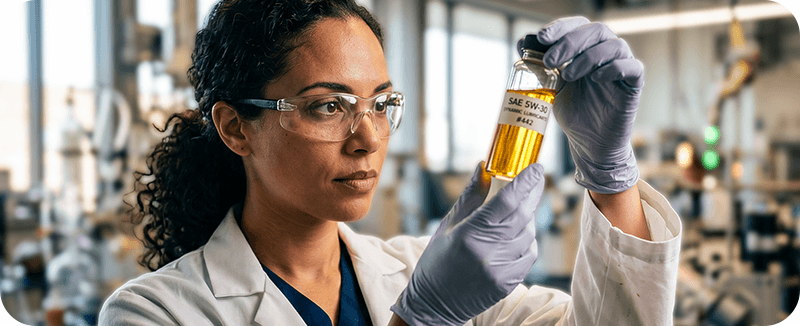 Investigadora analisa uma amostra de lubrificante em laboratório industrial. A imagem representa investigação, desenvolvimento de produtos, controlo de qualidade e inovação em soluções de lubrificação.