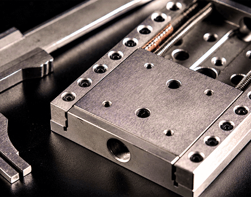Componente mecânico de guia linear de precisão utilizado em equipamentos industriais. A imagem representa sistemas de movimento linear, automação industrial e lubrificação de guias e barramentos.