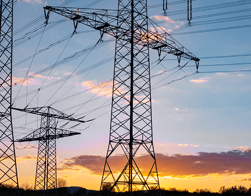 Linhas de transmissão elétrica e torres de alta tensão ao pôr do sol. A imagem representa distribuição de energia, transformadores, equipamentos elétricos e infraestrutura energética.