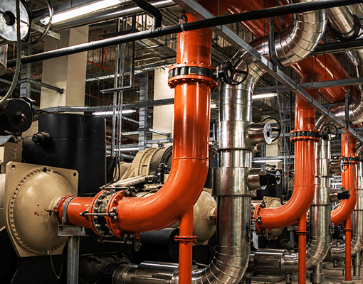 Sistema industrial de tubagens e permutadores térmicos utilizado para controlo de temperatura. A imagem representa fluidos de transferência de calor e processos térmicos industriais.