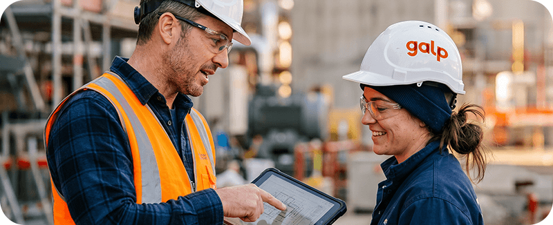 Dois profissionais da Galp consultam informação técnica num tablet em ambiente industrial. A imagem representa apoio técnico, soluções personalizadas, colaboração operacional e serviços para a indústria.