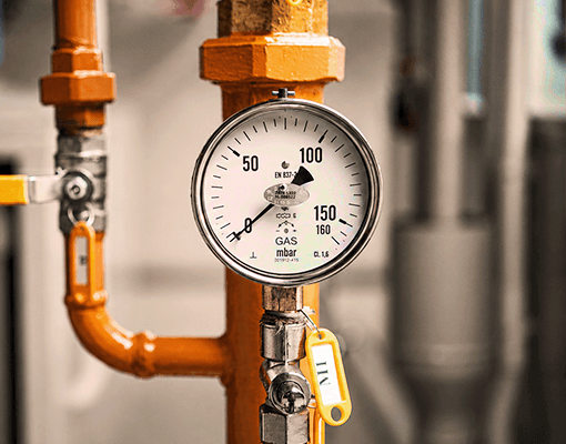 Manómetro instalado numa tubagem industrial para monitorização de pressão. A imagem representa sistemas de ar comprimido, controlo de pressão e eficiência operacional.