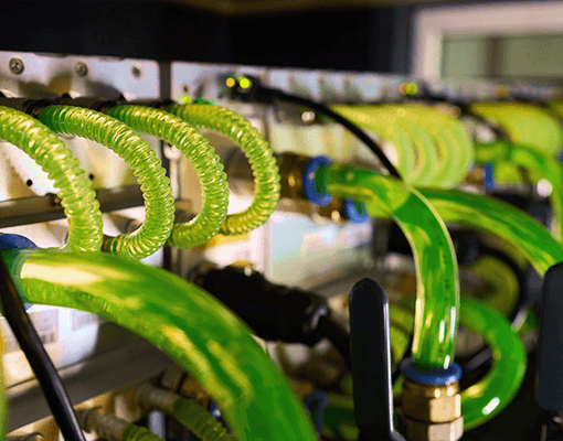 Tubagens industriais com fluido de refrigeração em circulação num sistema de arrefecimento. A imagem representa compressores frigoríficos, refrigeração industrial e transferência térmica.