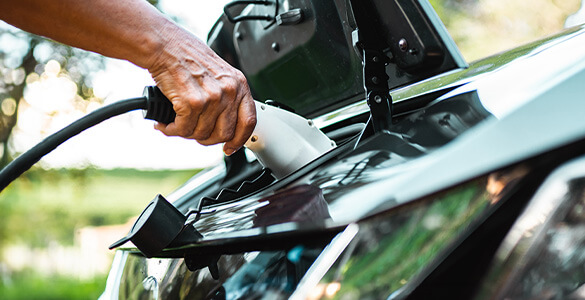 Primer plano del puerto del cargador del automóvil, con un cargador insertado y una mano sosteniéndolo.